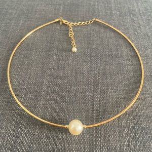 Gold necklace with a pearl in the center of it